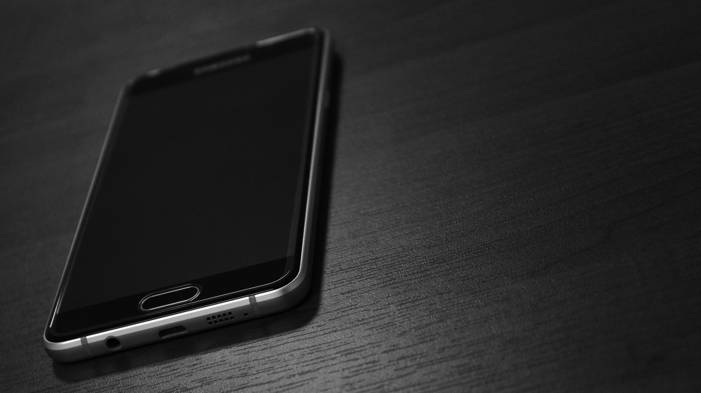 Smartphone di atas meja gelap, servis iPhone dan Android profesional di Servisin Kuy